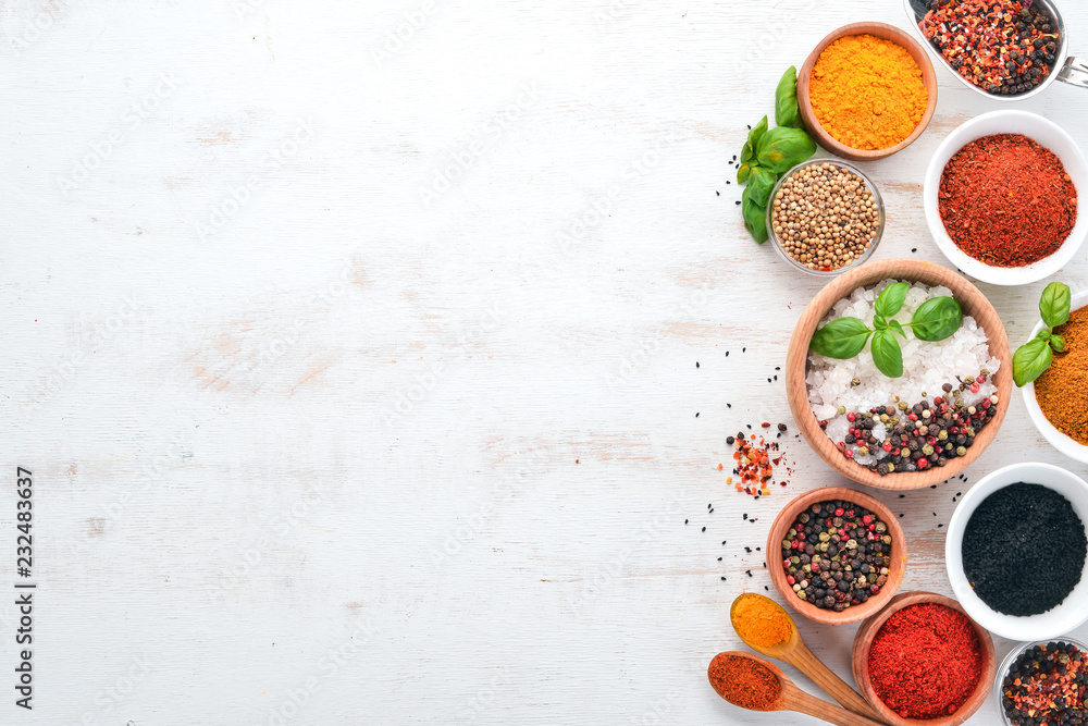 A set of Spices and herbs on a white wooden table. Basil, pepper, saffron, spices. Indian traditional cuisine. Top view. Free copy space. - obrazy, fototapety, plakaty 