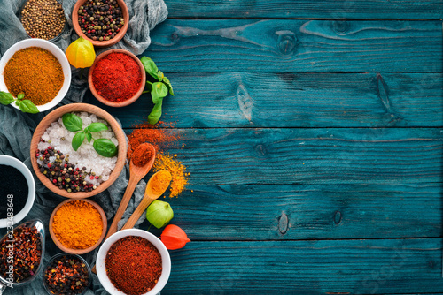 Spices and herbs on a blue wooden table. Basil, pepper, saffron, spices. Indian traditional cuisine. Top view. Free copy space.