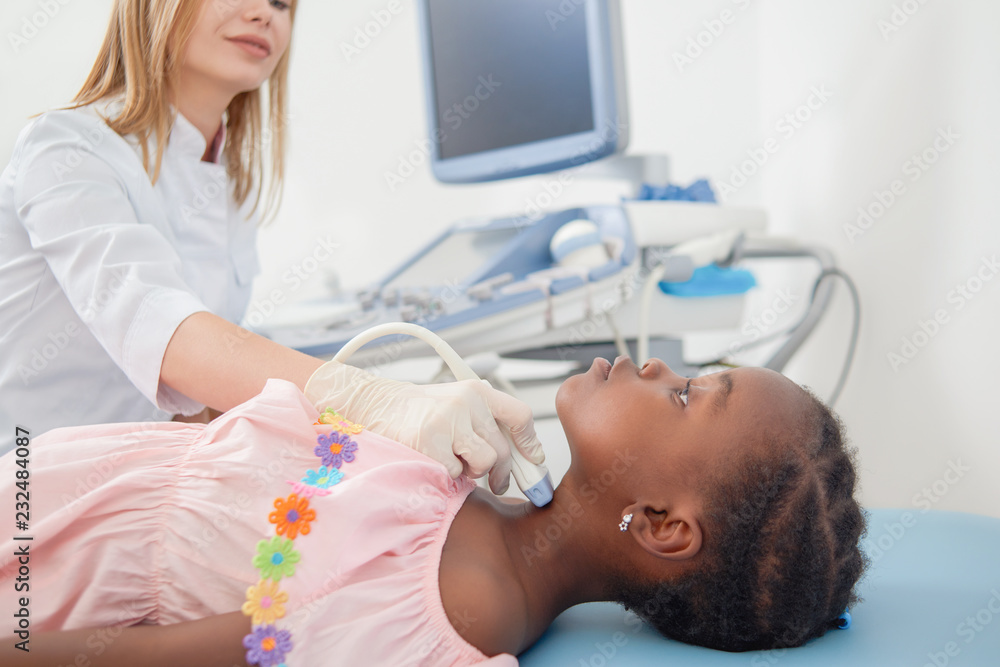 Afro child lying when doctor scanning her neck. Afro child lying when doctor scanning her neck.