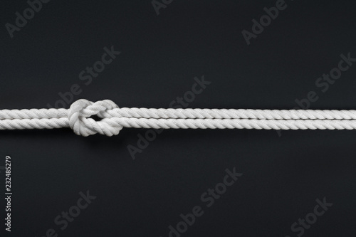 White ship ropes connected by reef knot on black