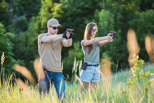 the instructor teaches the girl to shoot a pistol at the range