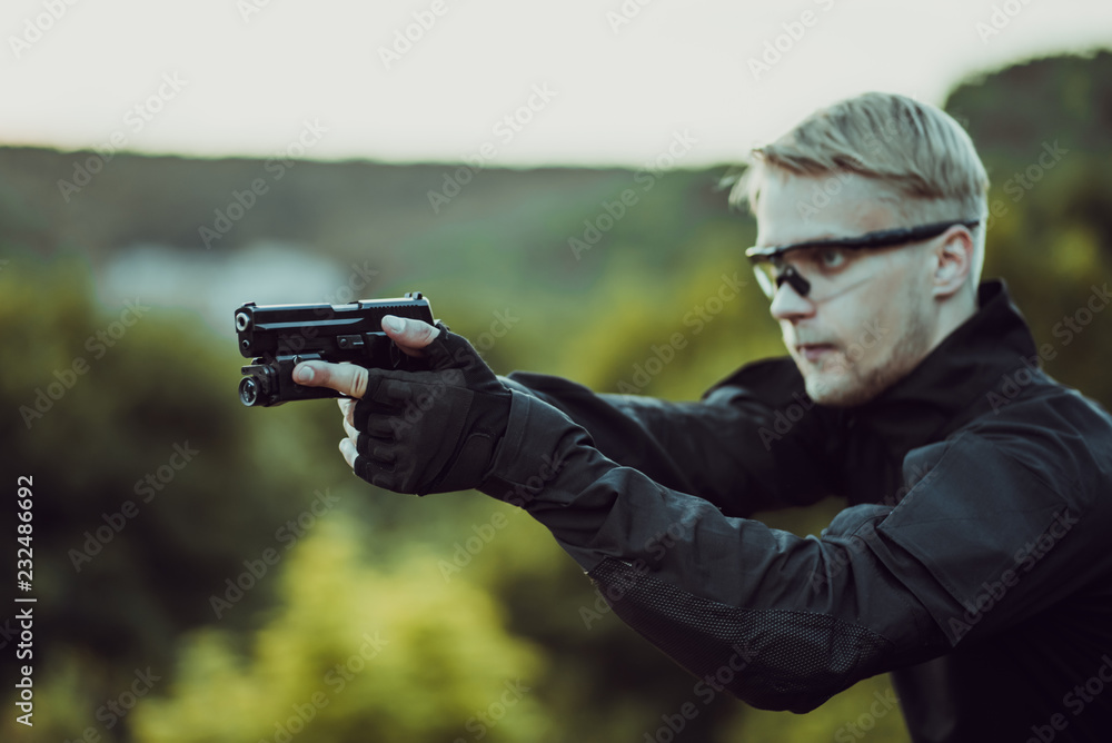 instructor with gun in forest leads aiming and posing on camera instructor with gun in forest leads aiming and posing on camera