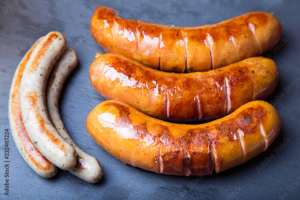 Grilled sausages on black board. Close-up, selective focus. Grilled sausages on black board. Close-up, selective focus.