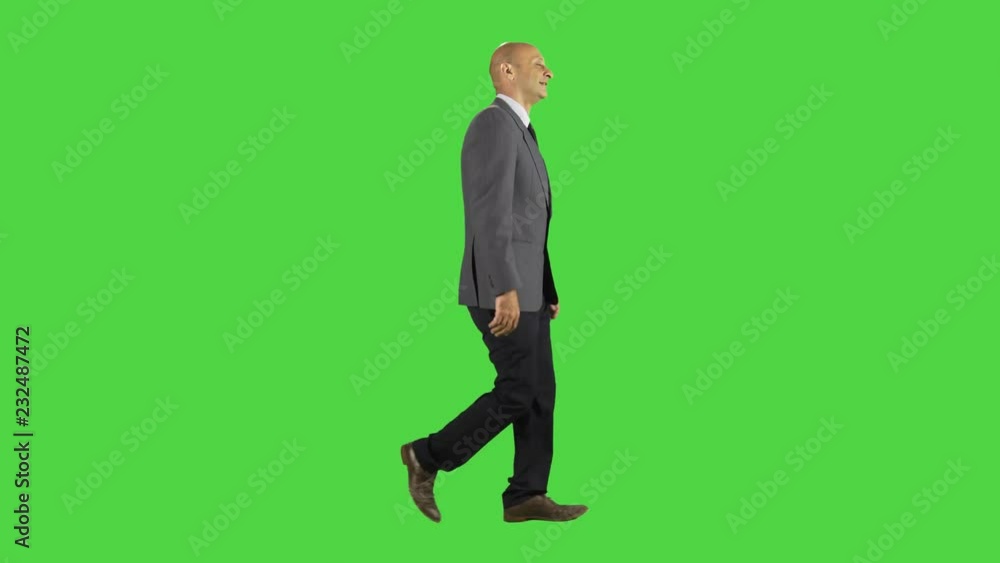 Businessman walking and smiling, calls someone to join him, wearing a suit. full sideways shot over a green screen. Businessman walking and smiling, calls someone to join him, wearing a suit. full sideways shot over a green screen.