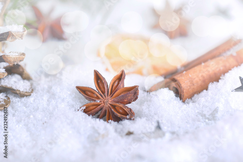anise star and cinnamon on snow and  lights christmas decoration