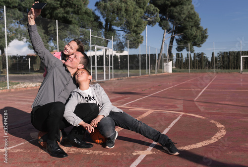 Father taking selfie with his children at basketball court