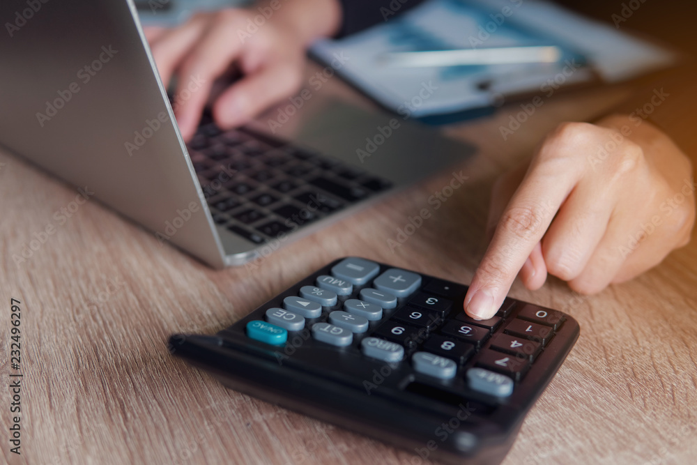 Business financial manager using calculator and laptop for analyzing finance graph data in office. successful concept. Business financial manager using calculator and laptop for analyzing finance graph data in office. successful concept.