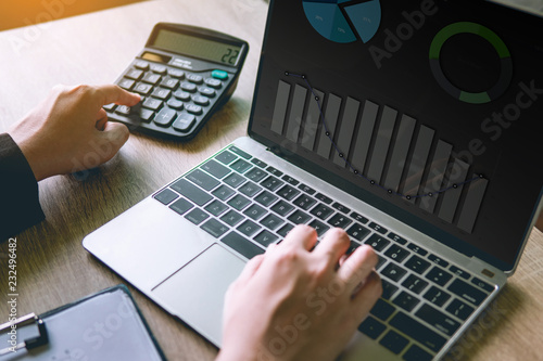 Business financial manager using calculator and laptop for analyzing finance graph data in office. successful concept.