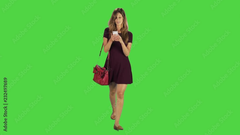 A young woman walking towards camera, answering a phone call in a full body shot over a green screen. A young woman walking towards camera, answering a phone call in a full body shot over a green screen.