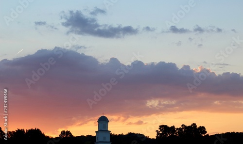 Fototapeta Naklejka Na Ścianę i Meble -  The orange evening sky over the steeple of the courthouse.
