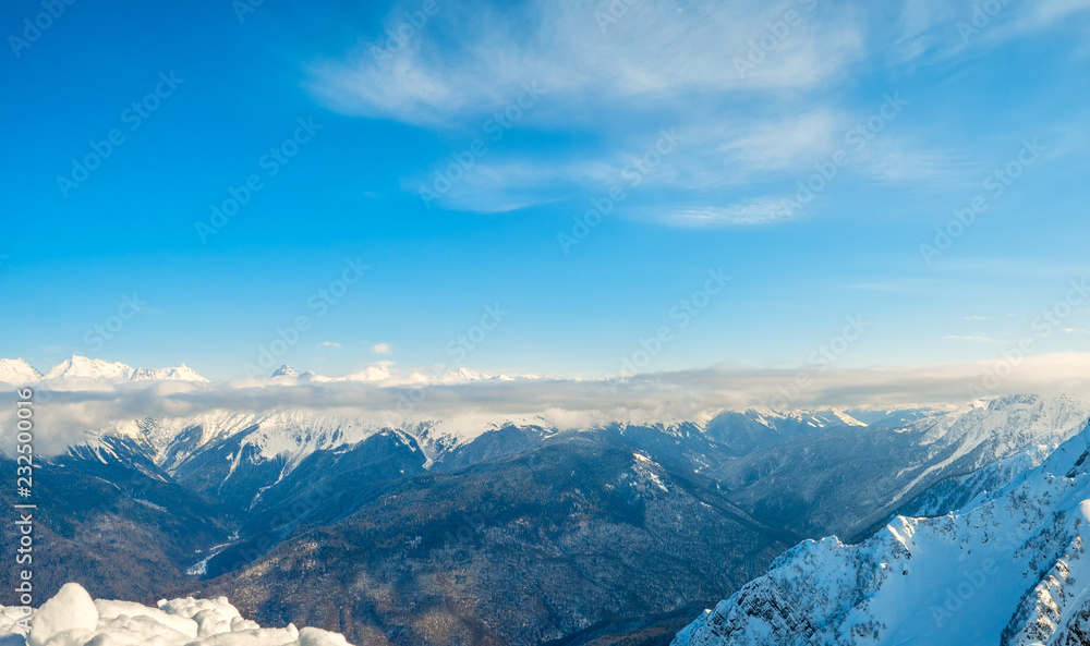 Beautiful snowy ridge of caucasus mountains under clear blue sky in Krasnaya Polyana, Russia.