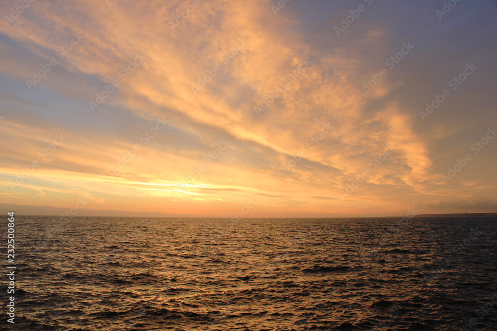 Sky Nature View of Sunset Over Calm Sea Water with Vibrant Orange Cloudscape. Beautiful Sky Background at Sunset or Sunrise, Dusk and Dawn Panoramic Skyline View with Still Water on Summer Season Day