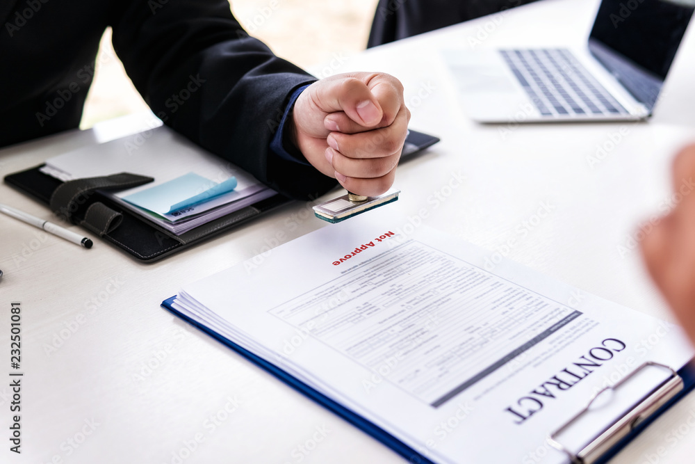 Business man sitting with hand holding stamp not approve important contract Insurance documents for house and family in office. Business man sitting with hand holding stamp not approve important contract Insurance documents for house and family in office.