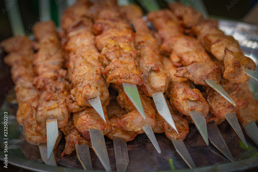 Fresh kebabs on skewers, selective focus, background with vignette. Grill on charcoal and flame, picnic, street food