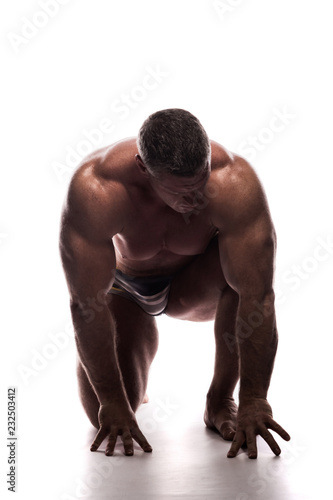 large powerful man showing his muscles in the Studio without a shirt on white background, sitting on his knee