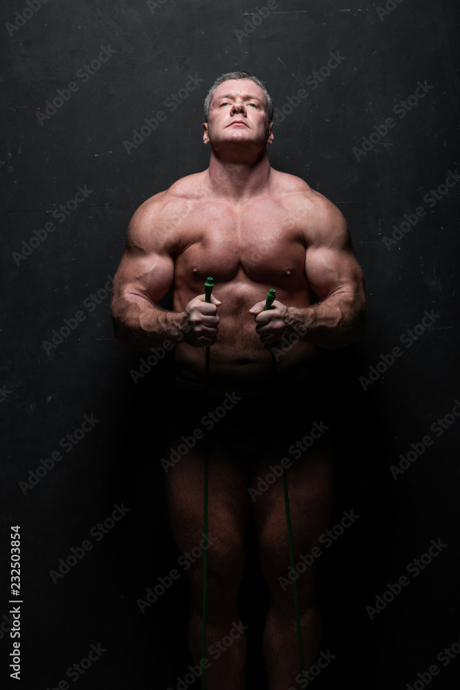 Fototapeta premium powerful man trains his muscles in a shirtless Studio on a grunge black wall