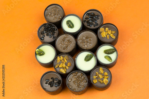 Chocolate candies on a colored background. Candies with different fillings laid out on a color table.