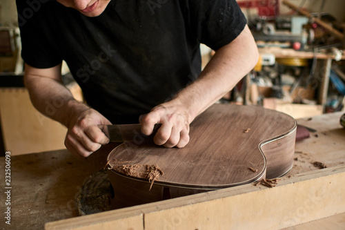 The luthier shuffles the body of a classical guitar.