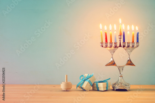 image of jewish holiday Hanukkah background with traditional spinnig top, menorah (traditional candelabra) and burning candles.