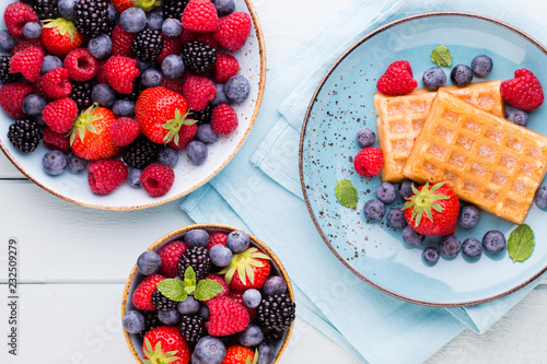 Fresh berry salad on blue dishes. Vintage wooden background.