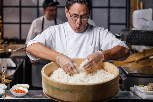 young emotional man is happy to prepare rice. funny chef is singing songs while cooking rice for sushi. close up photo