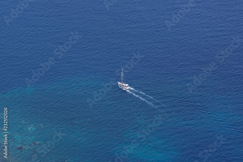 View from above on the single sailing boat in open sea
