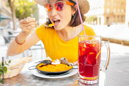 Young traveler woman eating spanish dinner sea Paella and sangria fruit wine during siesta