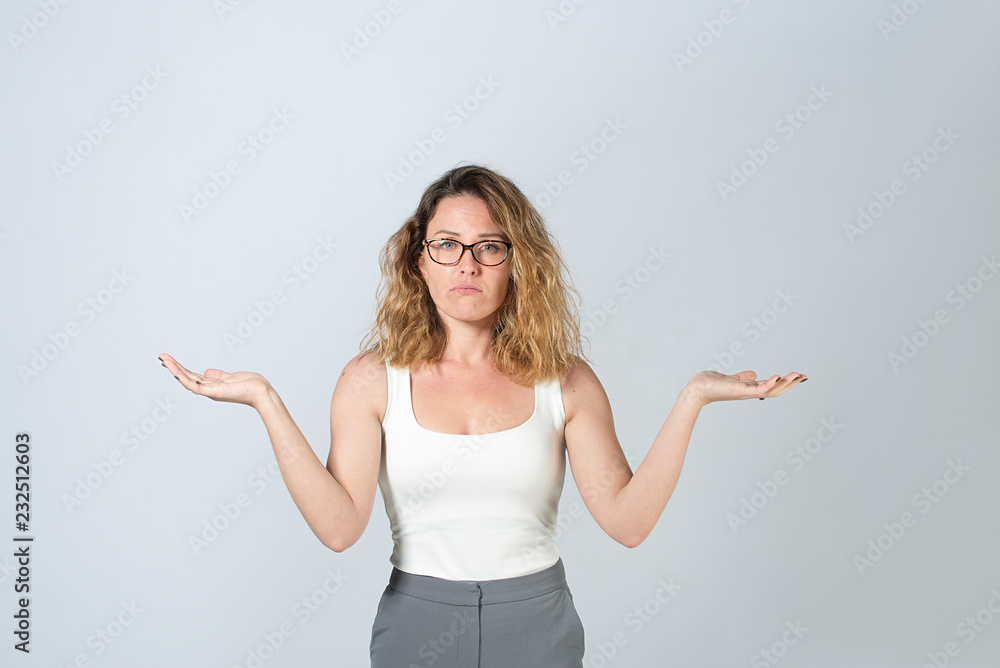 Young business woman in a white T-shirt and gray pants. beautiful lady with glasses spread her arms to the side. on gray background Young business woman in a white T-shirt and gray pants. beautiful lady with glasses spread her arms to the side. on gray background