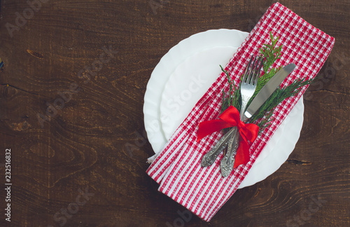 Christmas dark wooden background with christmas decoration, fir branch. Table set with fork and knife.