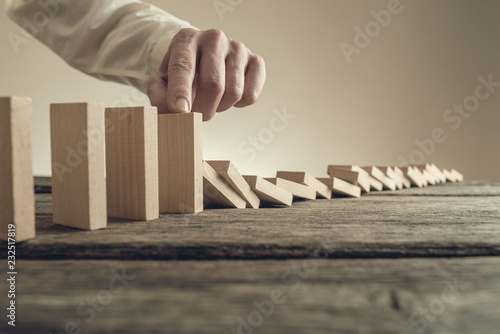 Tableau sur toile Businessman stopping collapsing wooden dominos