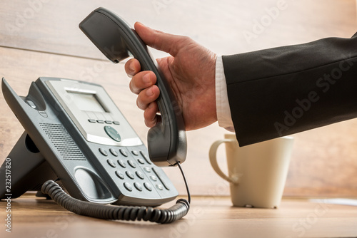 фотографія Closeup of businessman hanging or picking up a landline telephone handset