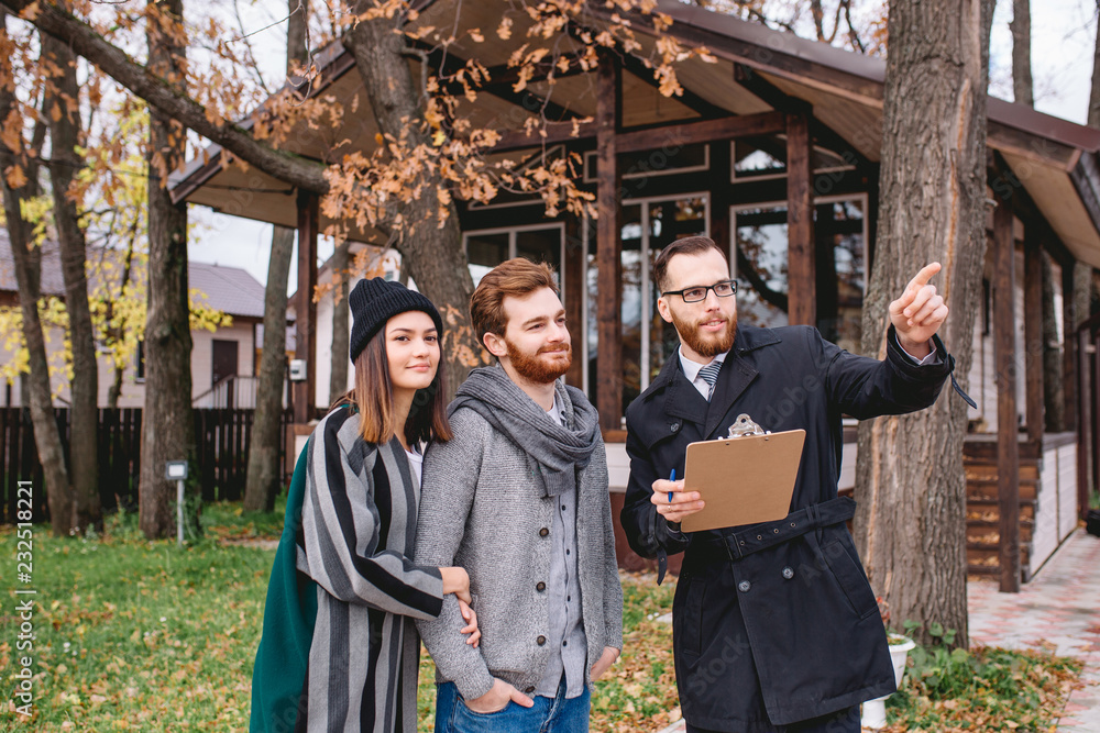Confident real-estate agent showing house plan on paper tablet to young caucasian couple, enchanted by the new house. Confident real-estate agent showing house plan on paper tablet to young caucasian couple, enchanted by the new house.