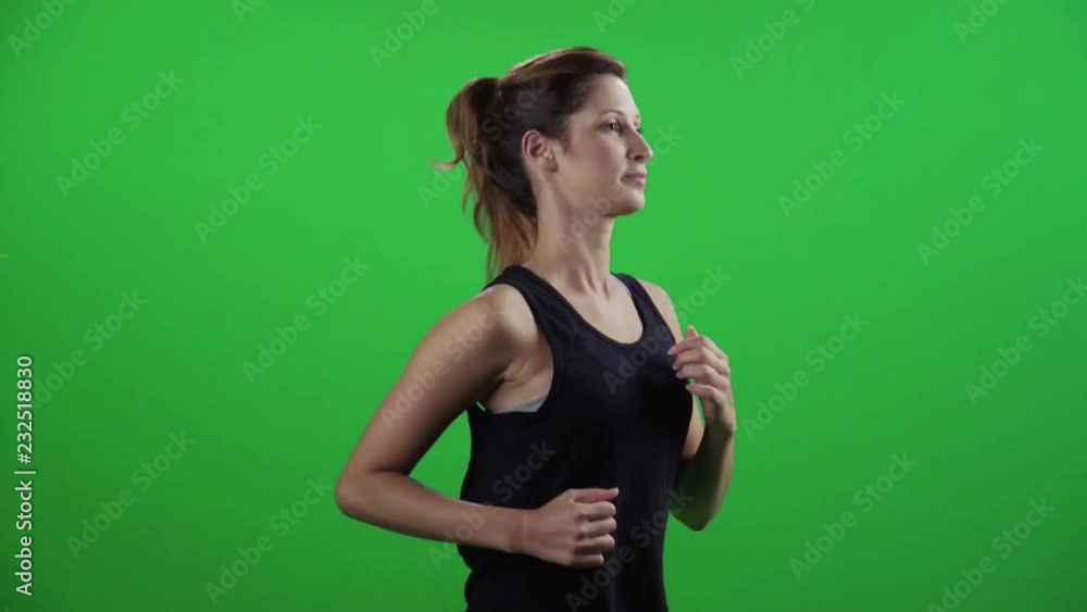 Young woman jogging in a medium frontal shot over a green screen, smiles. Young woman jogging in a medium frontal shot over a green screen, smiles.