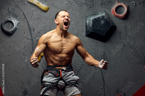 Foto Extreme sports or hobby concept- athletic climber with naked torso screaming on peak of overwhelming emotions, celebrating triumph