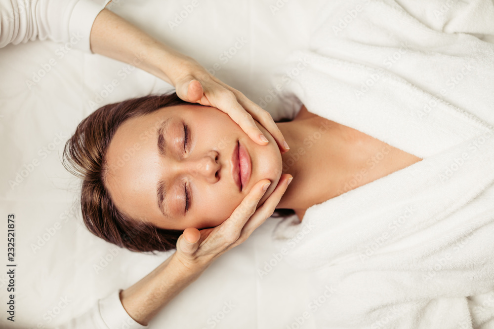 Naklejka premium healthy face skin. young beautiful girl receiving a massage for face. top view photo. free time