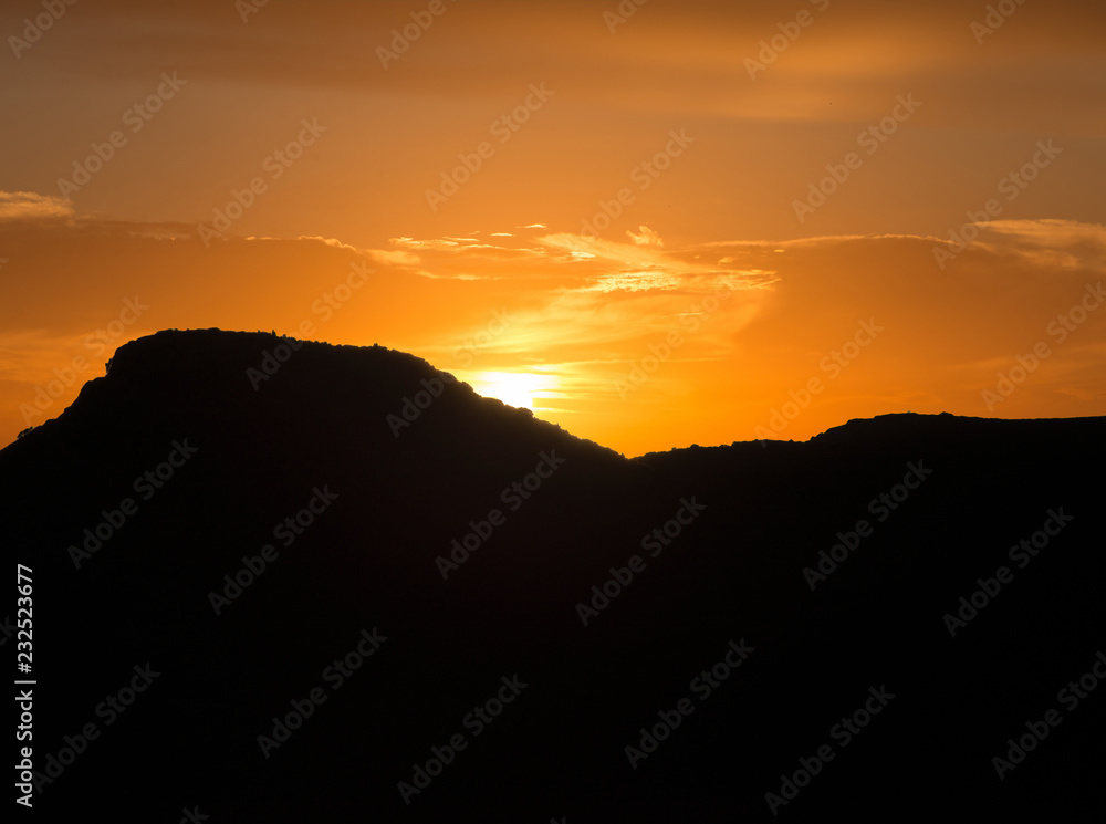 Sunset behind the silhouette of a mountain