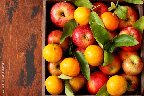 Fresh apples and tangerines in a wooden box