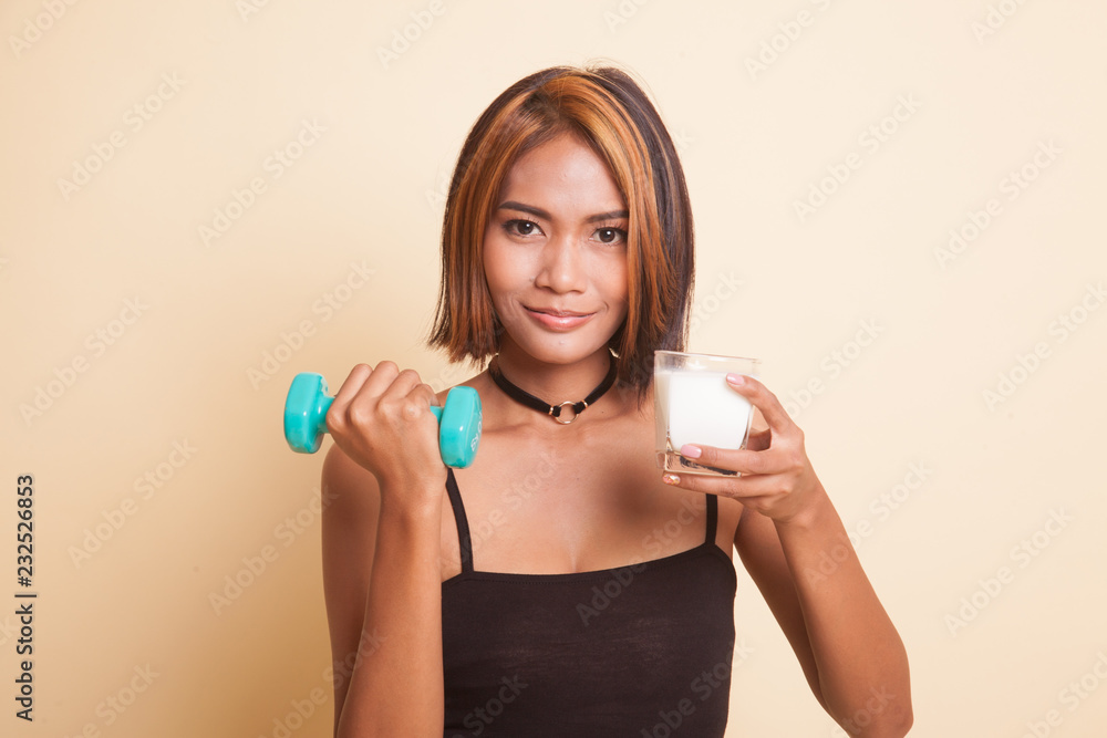Healthy Asian woman drinking a glass of milk and dumbbell. Healthy Asian woman drinking a glass of milk and dumbbell.