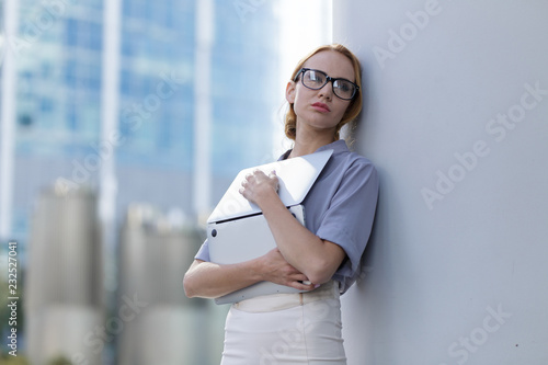 Sad girl standing with a laptopin the middle of the business word. A woman fired from her job photo