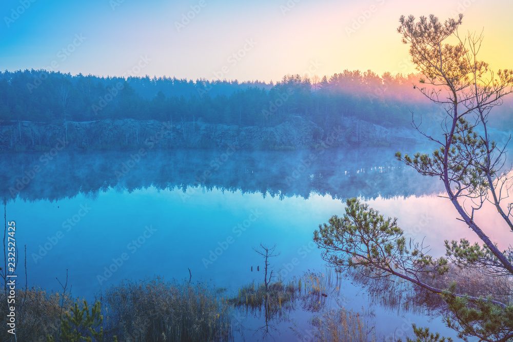Early in the morning, sunrise over a forest lake with steep shores