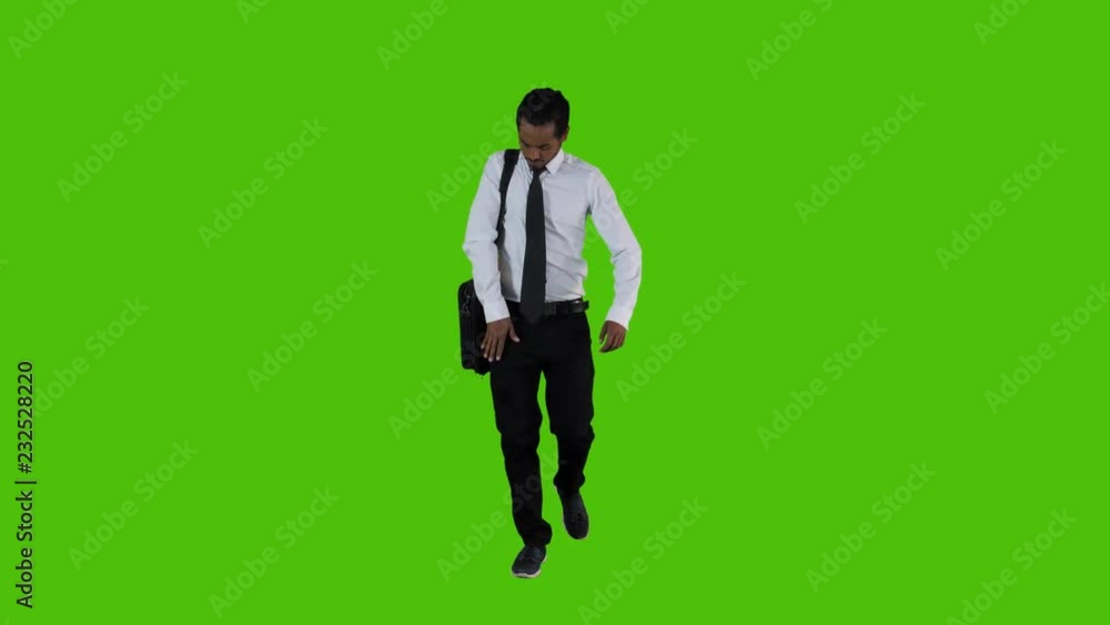 Answering a phone call while walking by a young businessman over a green screen. long frontal shot. Answering a phone call while walking by a young businessman over a green screen. long frontal shot.