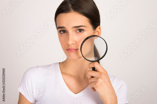 Young girl unhappy with having skin problems. holding magnifier face skin close up