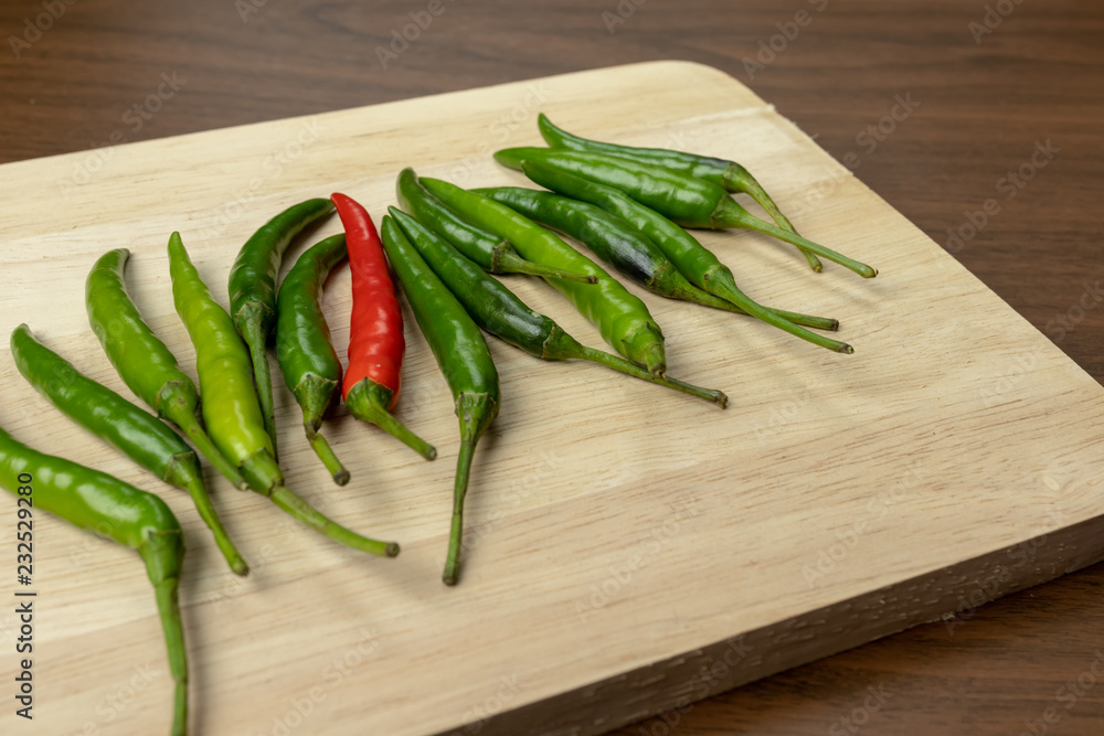 Green and red chili is a small piece on wooden floor. Green and red chili is a small piece on wooden floor.
