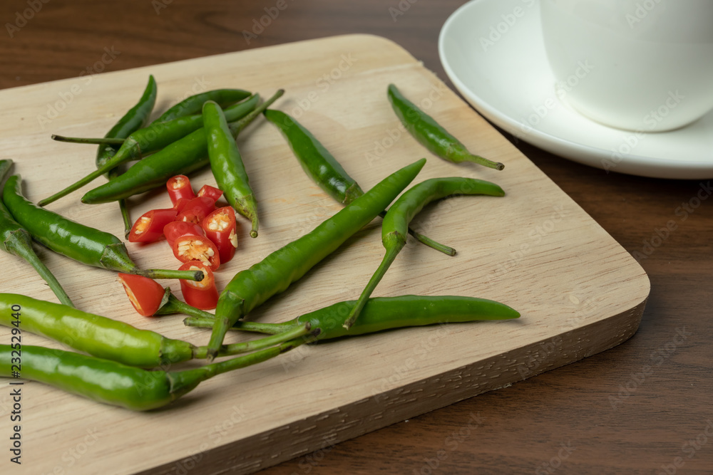 Green and red chili is a small piece on wooden floor. Green and red chili is a small piece on wooden floor.