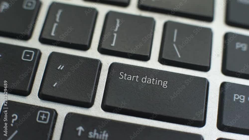 Start dating button on computer keyboard, female hand fingers press key Start dating button on computer keyboard, female hand fingers press key