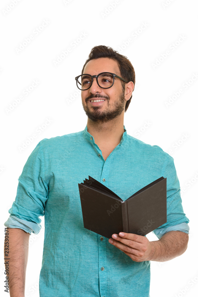 Young happy Indian man holding book while thinking Young happy Indian man holding book while thinking