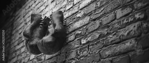 Photo Old boxing gloves hang on nail on brick wall with copy space for text