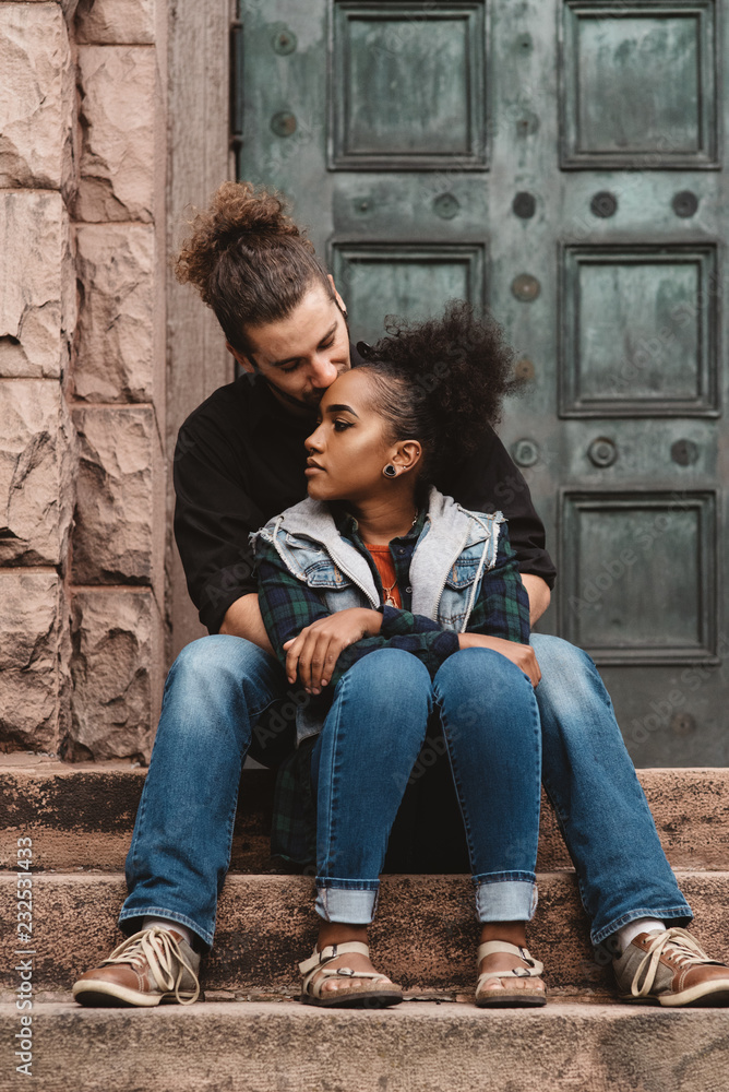 Man kissing woman while sitting on steps outdoors Man kissing woman while sitting on steps outdoors
