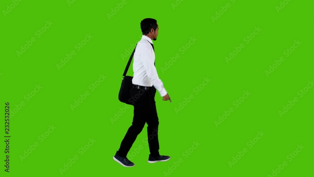 Extremely Happy young businessman walking and waving around over a green background, side long shot. Extremely Happy young businessman walking and waving around over a green background, side long shot.