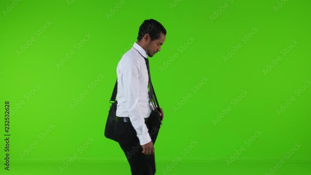 Sad ill and depressed businessman walking with a bag upset over a green background. Medium side shot. Sad ill and depressed businessman walking with a bag upset over a green background. Medium side shot.